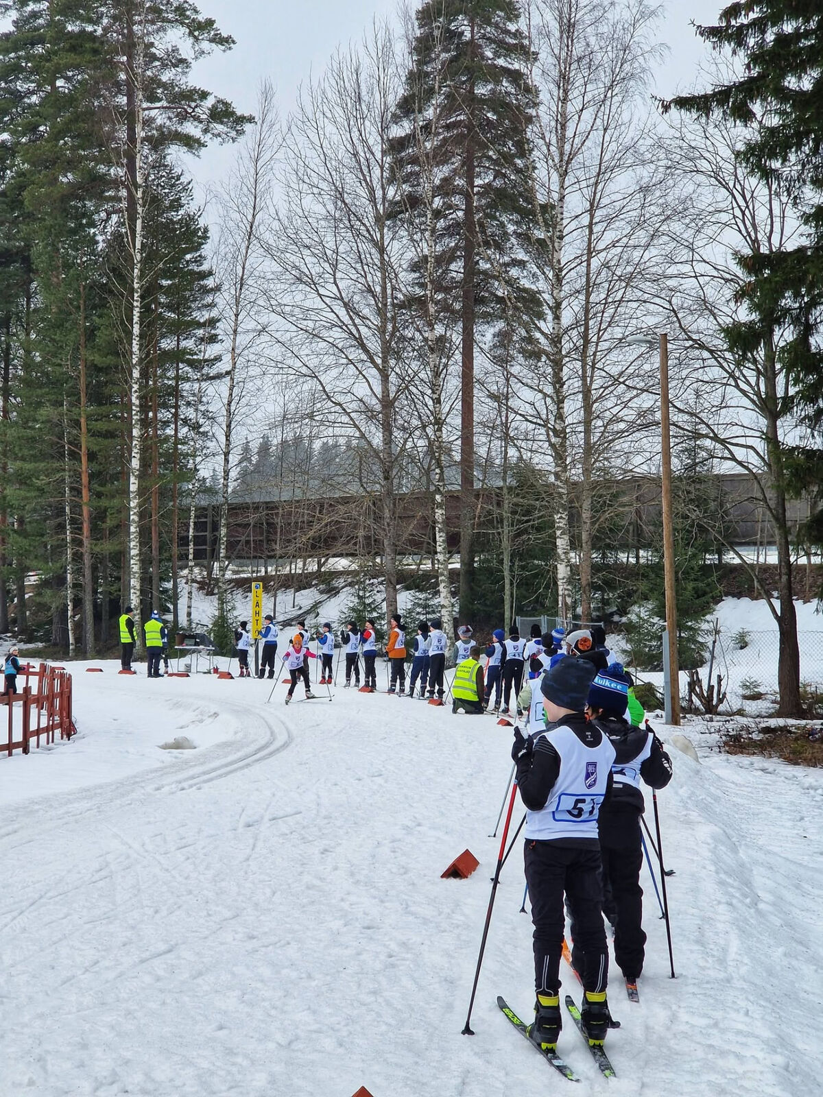 Young skiers in bibs lining up at a winter start area